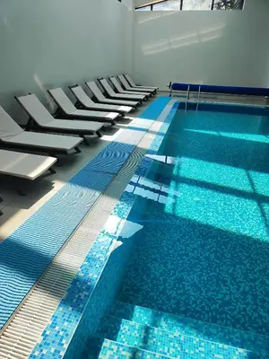 a large swimming pool with white chairs and a blue floor at Aspen Resort Studio I306 in Razlog