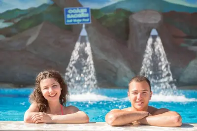 a man and a woman sitting in a swimming pool at SPA Hotel Elbrus in Velingrad