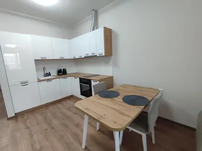 a kitchen with a wooden table and white cabinets at Pana Green Residence in Panagyurishte