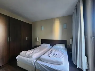 a bedroom with a large bed with white sheets at Pirin View Apartment in Bansko
