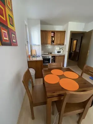 a kitchen with a wooden table with chairs and a dining room at St John Hill Alexander Services Apartments in Bansko