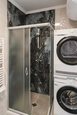 a shower with a glass door next to a washing machine at Apartment Aria 3 in Velingrad