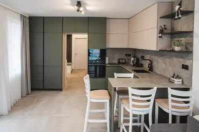 a kitchen with green cabinets and a counter with stools at Apartment Aria 3 in Velingrad