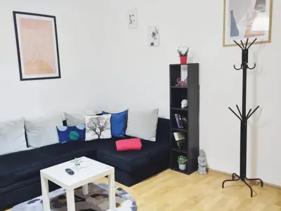 a living room with a black couch and a white table at Apartment for four next to blvd Vitosha in Sofia