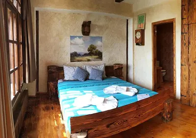 a bedroom with a large wooden bed with blue sheets at Самостоятелна къща за гости с изглед към планината Вила Марк in Kraevo