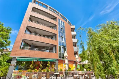 a tall brick building with trees in front of it at Hotel Elit in Sandanski