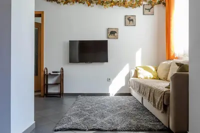 a living room with a couch and a tv on a wall at Best Location in Sofia Center in Sofia
