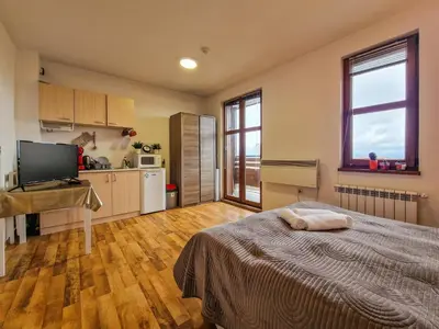 a bedroom with a bed and a desk and a kitchen at Mountain View Studio, Steps from Bansko Gondola by Flat Mаnager in Bansko