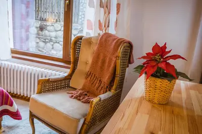 a wicker chair sitting next to a table with a vase at Cozy Luxurious Apartment Next to Borovets and Rila mountain in Govedartsi