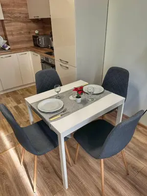 a white dining table with chairs and plates and glasses at 5 min from the Airport in Sofia