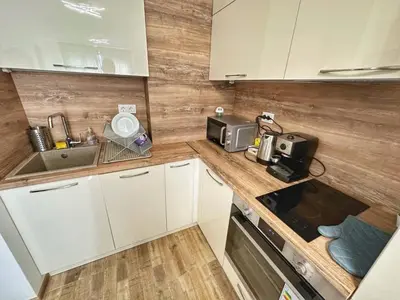 a small kitchen with white cabinets and a sink at 5 min from the Airport in Sofia