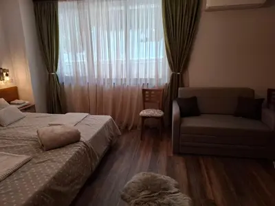 a bedroom with a bed and a chair and a window at Двуспален апартамент Милена в хотел Росица,Пампорово in Pamporovo