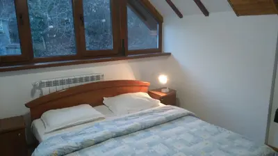 a bedroom with a bed with a wooden headboard and windows at Tora Bora Guest House in Pancharevo