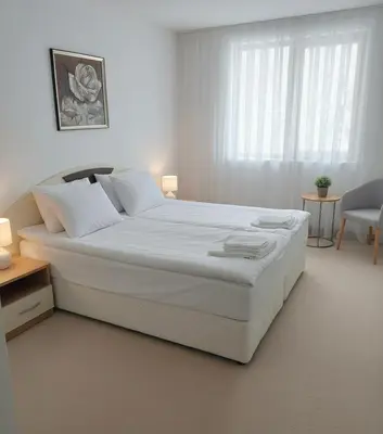 a white bedroom with a large bed with white sheets at Raya Apart Pamporovo in Pamporovo