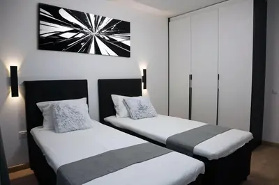 two beds in a room with white walls at Luxury Apartment 5 Mins from Slopes Parking in Bansko