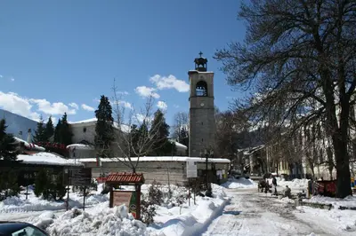 a snow covered street with a clock tower at Luxury Apartment 5 Mins from Slopes Parking in Bansko