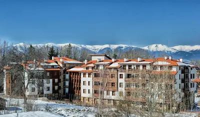 a large building in the snow with mountains in the background at Bansko holiday apartments - Mountain View Resort in Bansko