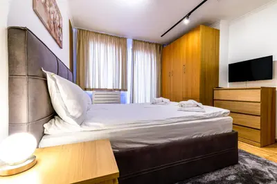 a hotel room with a bed and a flat screen tv at Yeti Apartment Pamporovo Grand Monastery in Pamporovo