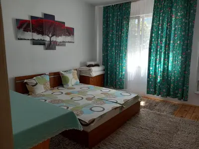 a bedroom with a bed and a window with green curtains at ViBo Guesthouse in Sapareva Banya