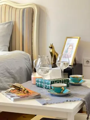 a table with two glasses and plates on a bed at Christine's Apartment in Sofia