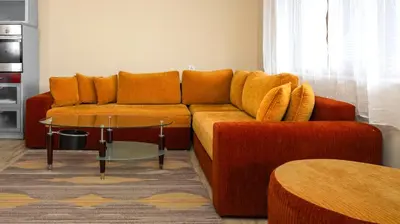 an orange couch in a living room with a table at Penthouse Astralis - Pamporovo in Pamporovo