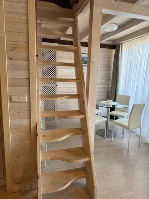 a wooden spiral staircase in a room with a table at Pirin Golf SP Apartments in Razlog
