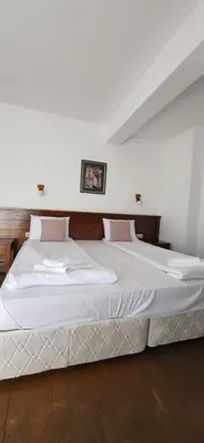 a bedroom with a bed with white sheets and pink pillows at Banderitsa Hotel and Casino in Bansko