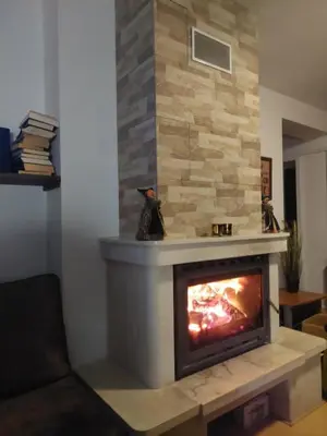 a fireplace in a living room with a stone wall at Уютен апартамент за зимна почивка в Пампорово in Pamporovo