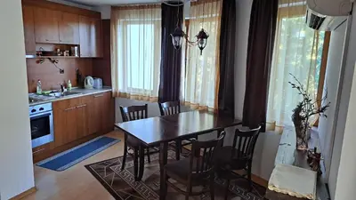 a kitchen with a table and chairs in a kitchen at Уютен апартамент за зимна почивка в Пампорово in Pamporovo