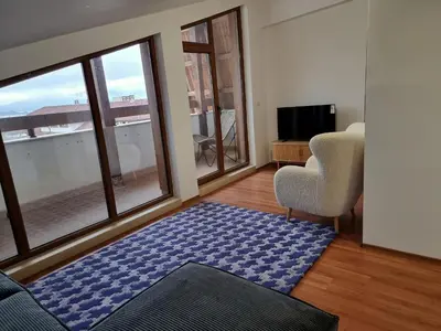 a living room with a couch and a large window at Belvedere private apartment 1-bedroom with balcony in Bansko