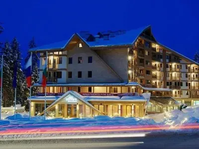 a large building in the snow at night at Ski Studio Hotel Iceberg in Borovets