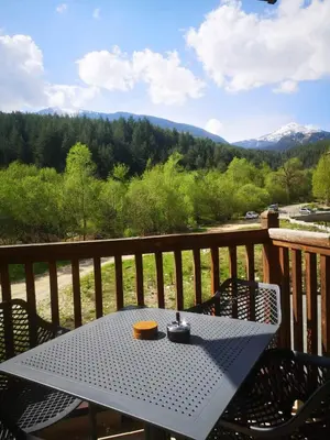 a table on a deck with a view of mountains at Woodsy views 1 bedroom apartment in Bansko