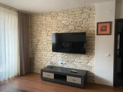 a living room with a television on a brick wall at Royal Towers Bansko Apartment - Gondola in Bansko