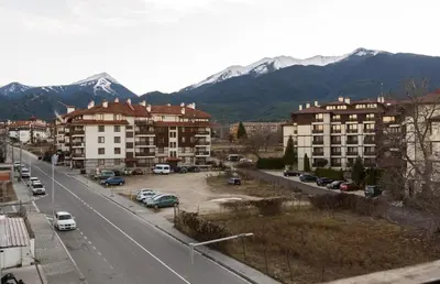 a city street with buildings and cars and mountains at Niki's cosy place in Bansko