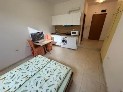 a small room with a bed and a kitchen at Basment Rooms - Todorini Kuli in Bansko