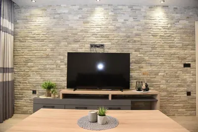 a living room with a large television on a brick wall at Апартамент Гончеви in Velingrad