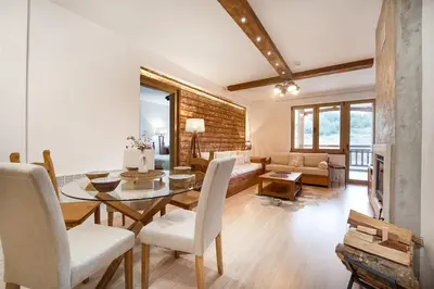 a dining room and living room with a table and chairs at Host2U Mountain 2 Bedrooms - Fireplace in Bansko