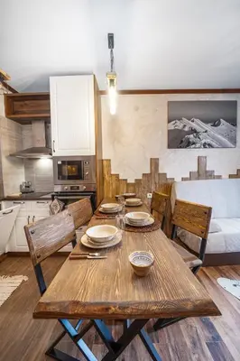 a wooden dining table with chairs and a kitchen at Host2U Authentic Bansko Apartment - Free Parking in Bansko