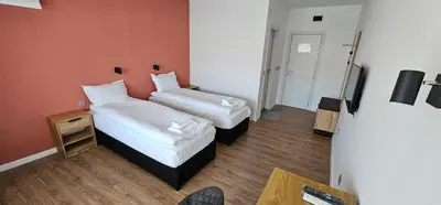a hotel room with two beds and a television at Къща за гости ЕСТЕТ ESTET Guest house in Oreshak