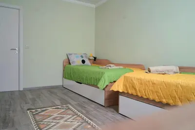 a bedroom with two beds with yellow and green sheets at Cozy Apartment in the Heart of Sofia, BG in Sofia