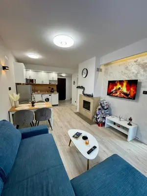 a living room with a blue couch and a fireplace at Pirin Cozy Escape 8 min walk from ski lift - Private Apartment Grand Bansko 1 in Bansko