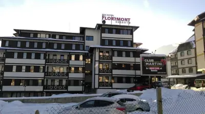 a snow covered building with cars parked in front of it at Bansko Apartment Next To The Ski Lift in Bansko