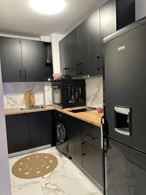 a kitchen with black cabinets and a refrigerator at Delux 2 - Plovdiv Модерен апартамент до Стария град и Източната порта in Plovdiv