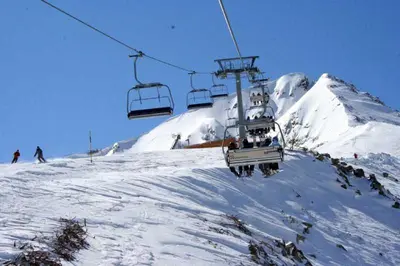 a group of people riding a ski lift in the snow at ELIA Apartment in Bansko