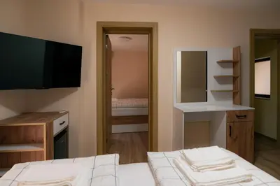 a room with a bed and a television and a bedroom at Къща за гости 'Кадийца' in Sushitsa