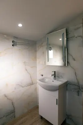 a white bathroom with a sink and a mirror at Къща за гости 'Кадийца' in Sushitsa
