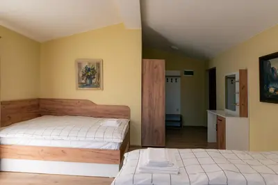 two beds in a room with yellow walls at Къща за гости 'Кадийца' in Sushitsa