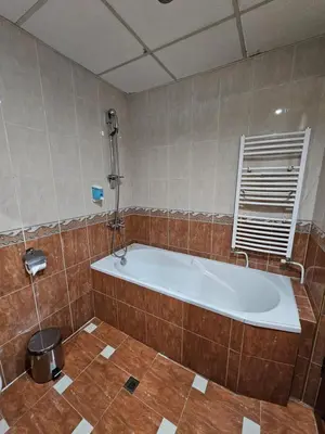 a bath tub in a tiled bathroom at Family Hotel Jeri in Velingrad