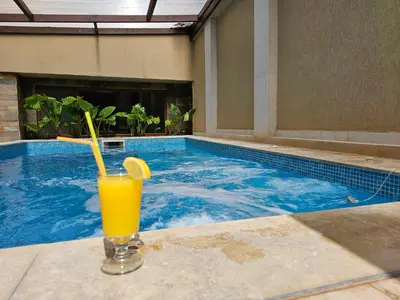 a glass of orange juice sitting next to a swimming pool at Family Hotel Jeri in Velingrad