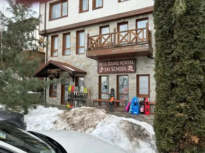 a building with a ski shop with snow in front of it at Green life Bansko -view one bedroom apartment in Bansko